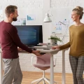 Kobieta i mężczyzna pracujący przy nowoczesnych biurkach elektrycznych LINAK w jasnym biurze.webp